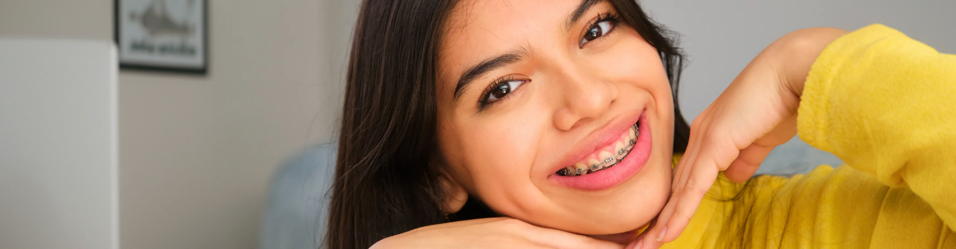 Smiling young woman wearing clear ceramic braces on her teeth.